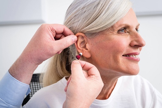 Eine ältere Frau erhält ein modernes Hörgerät zur Verbesserung des Hörvermögens.